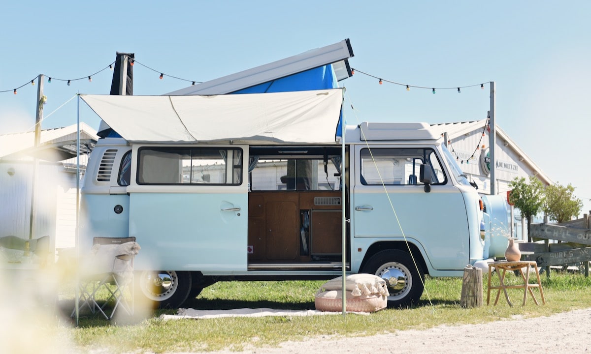Blauwe Volkswagen camper met een luifel ervoor