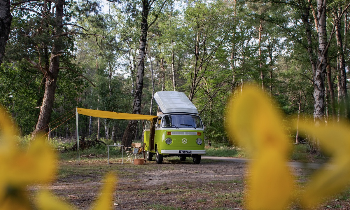 Volkswagen T2 met gele luifel in het bos